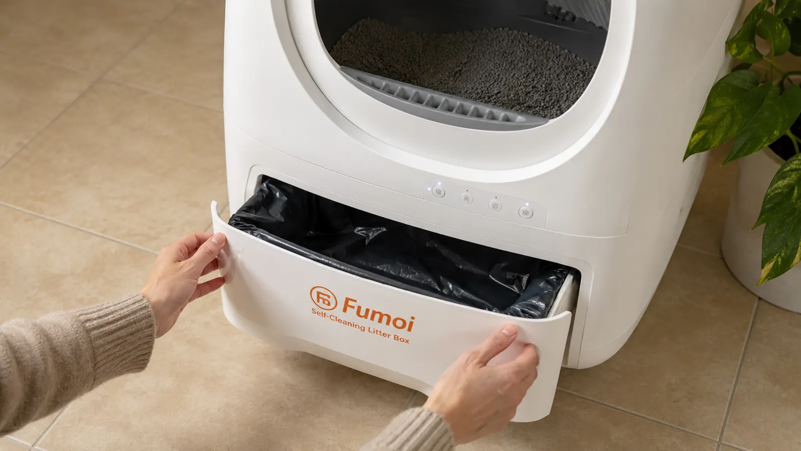 Hand pulling open the Fumoi waste drawer partway to reveal a sealed carbon-lined bag inside, tile floor visible below